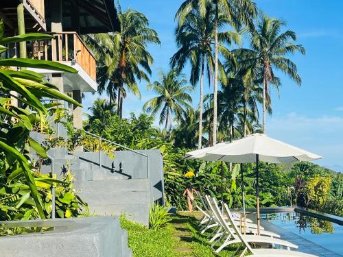 a resort with a pool and an umbrella and palm trees at Bintana sa Paraiso Binunsaran in Mambajao