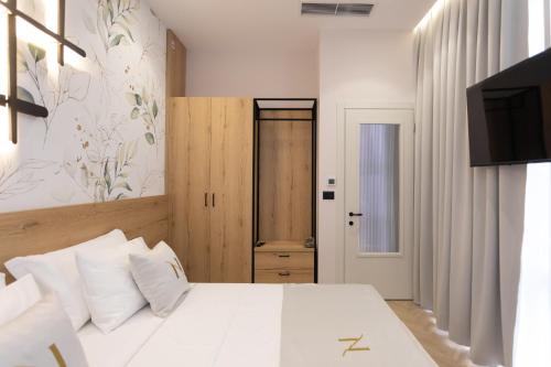 a bedroom with a white bed and a television at Nayel Hotel in Durrës