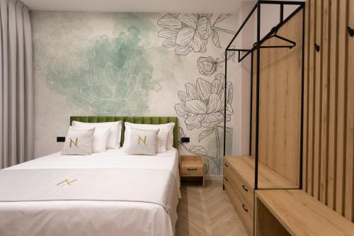 a bedroom with a large white bed and a wall with flowers at Nayel Hotel in Durrës