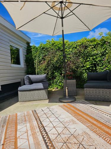 a patio with two couches and an umbrella at Witte Magnolia in Burgh Haamstede