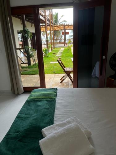 a bedroom with a bed with green sheets and a window at Pousada Quinta do Mar in Icapuí