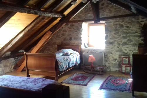 - une chambre mansardée avec un lit et une télévision dans l'établissement Les maisons d'Ustou., à Ustou