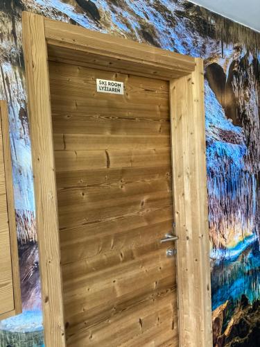 a wooden door with a sign on it in front of a mural at Apartment Jasná Otupné in Demanovska Dolina