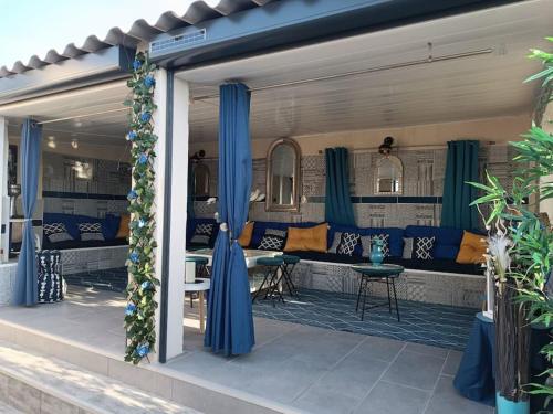 un patio avec des rideaux bleus et un canapé et des tables dans l'établissement Studio Blue House, à Vitrolles