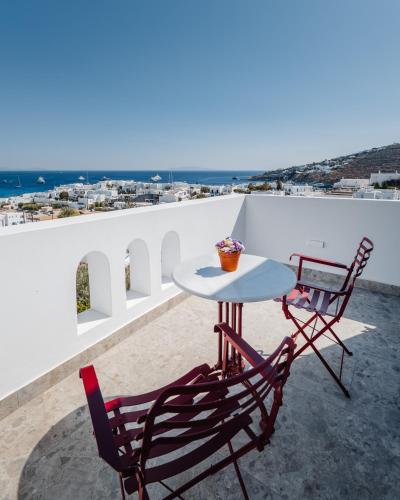 a table and two chairs on a balcony with a view at Pelican Bay Hotel in Platis Yialos Mykonos