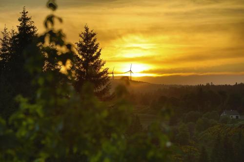 a sunset with wind turbines in the distance at Logis Hotel Spa Restaurant Le Provence in Lanarce
