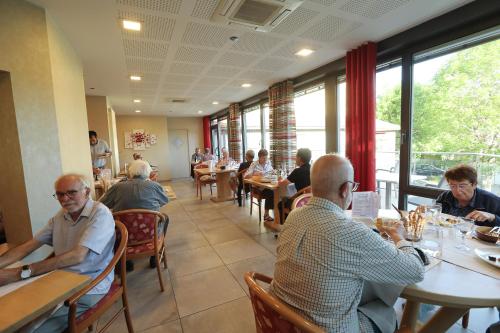 a group of people sitting at tables in a restaurant at Logis Hotel Spa Restaurant Le Provence in Lanarce