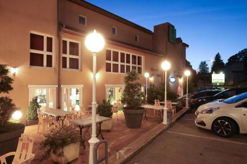 a car parked in front of a building with street lights at Logis Hotel Spa Restaurant Le Provence in Lanarce
