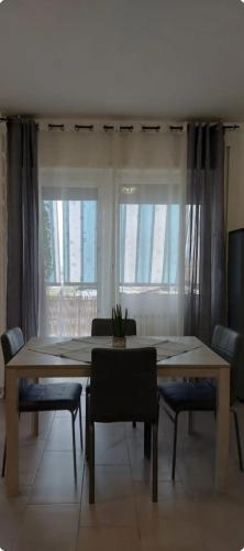 a dining room with a table and chairs and windows at House Arrow in Latina