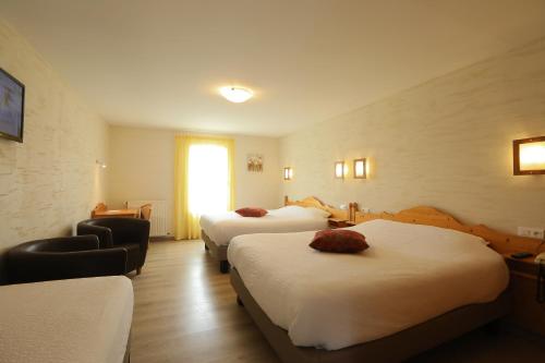 a hotel room with three beds and a window at Logis Hotel Spa Restaurant Le Provence in Lanarce