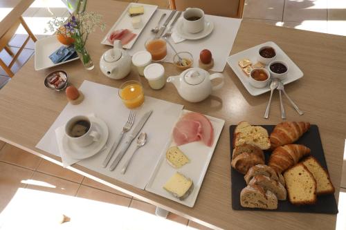 a table with a breakfast of bread and pastries at Logis Hotel Spa Restaurant Le Provence in Lanarce