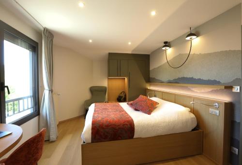 a bedroom with a bed and a desk and a window at Logis Hotel Spa Restaurant Le Provence in Lanarce