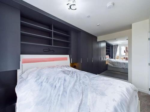 a bedroom with a large bed and a black wall at Luxury & Bright Apartment-Near Tube & Shops -Gym Access in Hatch End