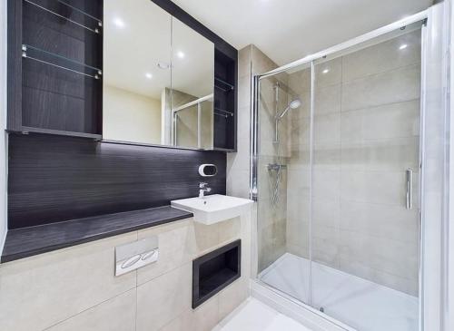 a bathroom with a shower and a sink and a mirror at Luxury & Bright Apartment-Near Tube & Shops -Gym Access in Hatch End