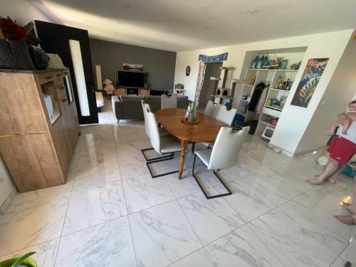 un salon avec une table en bois et des chaises blanches dans l'établissement Villa proche aérodrome les Pujols, à La Tour-du-Crieu