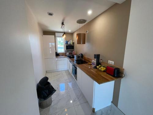 une cuisine avec des armoires blanches et un comptoir dans l'établissement Villa proche aérodrome les Pujols, à La Tour-du-Crieu