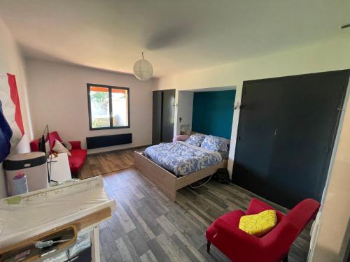une chambre avec un lit et une chaise rouge dans l'établissement Villa proche aérodrome les Pujols, à La Tour-du-Crieu