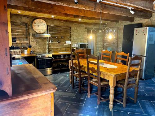 une cuisine avec une table en bois, des chaises et une horloge dans l'établissement Les Gîtes de Guernegroach - La Chaumière, à Langoëlan