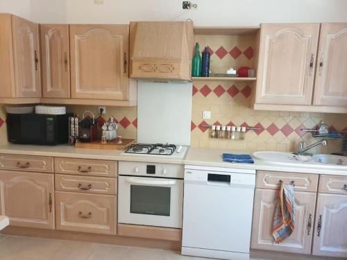 une cuisine avec des appareils électroménagers blancs et des armoires en bois dans l'établissement Maison de village chez corinne, à Besse-sur-Issole