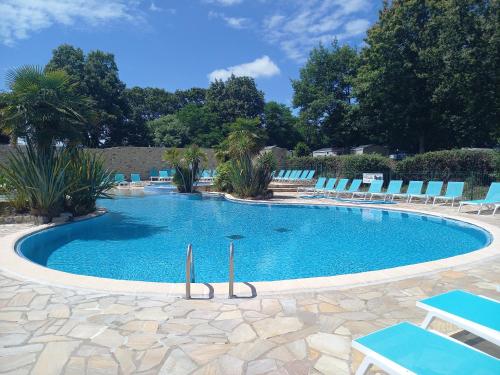 une grande piscine avec des chaises bleues et des arbres dans l'établissement mobil home camping 3 etoiles les ollivaud, à La Baule