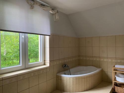 een badkamer met een bad en 2 ramen bij Apartament w Domu Wypoczynkowym Zacisze in Stegna