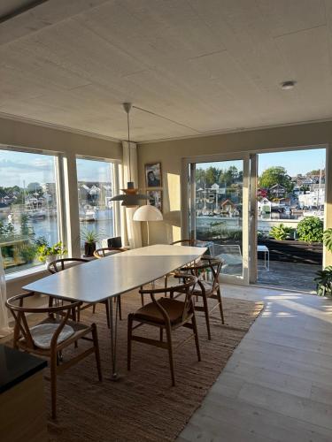 een eetkamer met een tafel, stoelen en ramen bij Lovely home in maritime surroundings near Stavanger in Stavanger
