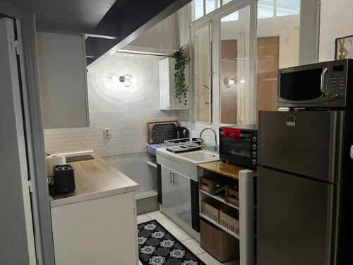 une petite cuisine avec un réfrigérateur et un micro-ondes dans l'établissement Le St Pierre Face au Château Appart in Nantes, à Nantes