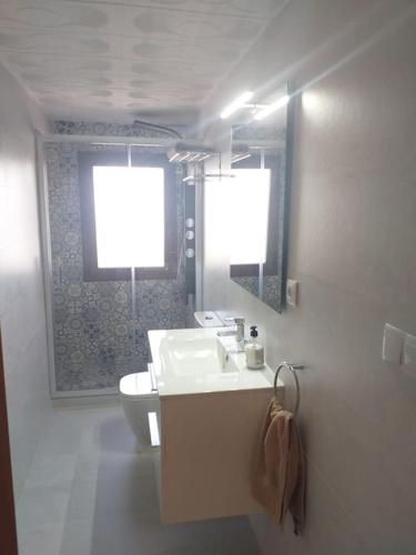 a bathroom with a sink and a toilet and two windows at Villa Carmeryl in Venta del Baúl