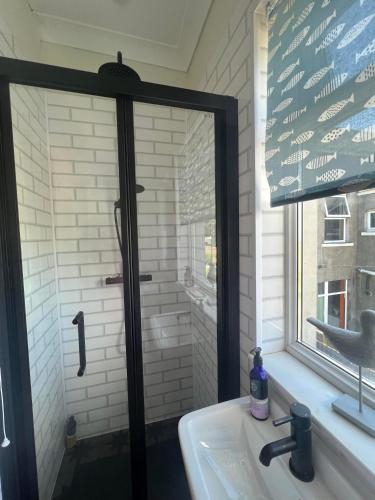 a bathroom with a mirror over a sink with a window at Ocean Reach in Porthcawl