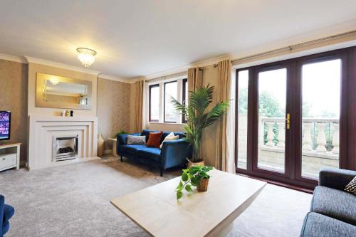 a living room with a blue couch and a fireplace at Spacious Dewsbury Home, 8 beds, sleeps 10, Free Parking and Wifi, 3 TVs, Close to motorways in Dewsbury