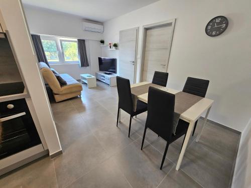 a living room with a table and chairs and a tv at Apartma Bertoki in Koper