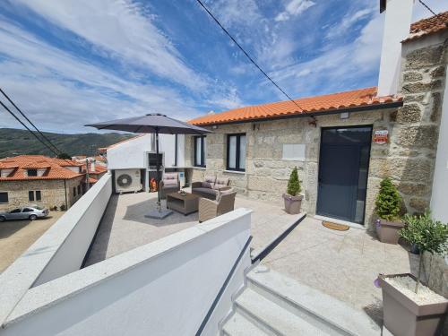 a balcony with an umbrella and a patio at Casa Dos Passadiços Do Mondego in Trinta