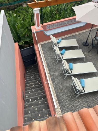 an outdoor patio with chairs and an umbrella and stairs at House of the sun in Ponta do Sol