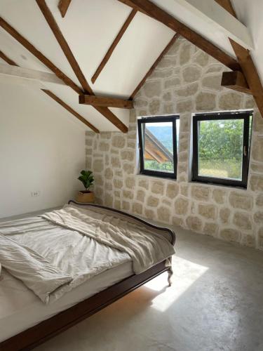 Un dormitorio con una cama grande en una pared de piedra. en House Joie, en Blaguša