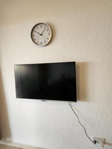 a clock on a wall above a television at Ocean Pearl in Peyia
