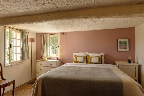 a bedroom with a large bed and two windows at La Bergerie in Bargemon