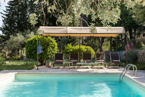 - une piscine avec des chaises, un parasol, une table et des chaises dans l'établissement La Bergerie, à Bargemon