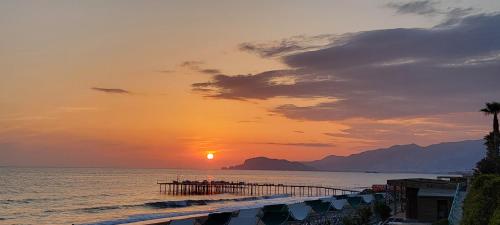 a sunset over a beach with a pier and the ocean at Jasminpark Villa in Alanya