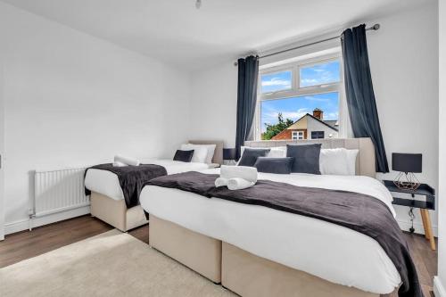 two beds in a bedroom with a window at Cozy Nook-Hot Tub, Sleeps 8, Free Parking, Netflix in Leicester