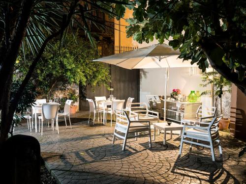 a patio with tables and chairs and an umbrella at Il Giardino di Ballarò Boutique B&B in Palermo