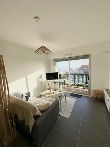 un salon avec un canapé et une grande fenêtre dans l'établissement La Bulle Marine, à Villers-sur-Mer
