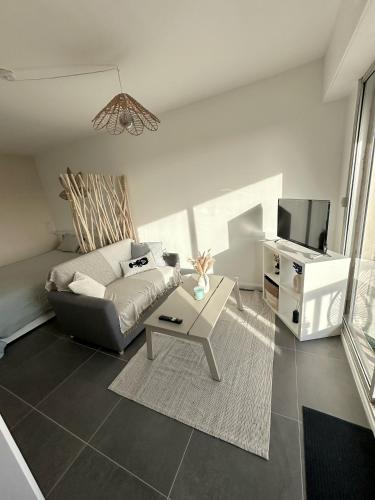 un salon avec un canapé et une télévision dans l'établissement La Bulle Marine, à Villers-sur-Mer