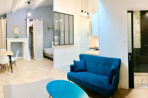 a living room with a blue couch and a table at Charmant studio au calme in Bordeaux