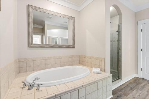 a white bathroom with a tub and a mirror at Coastal91 Free Golf Cart Gated Beach Access in Destin