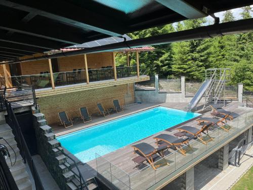 einen Außenpool mit Stühlen und einer Rutsche in der Unterkunft Transylvania Villa & Spa in Muntele Băişorii