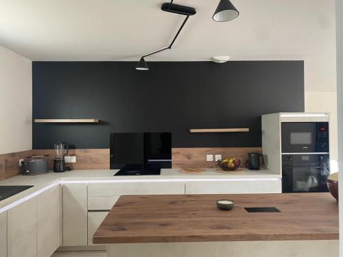 eine Küche mit weißen Schränken und einer schwarzen Wand in der Unterkunft La Clé des Champs Maison familiale à 15min Disneyland Paris WIFI GRATUIT in Boutigny