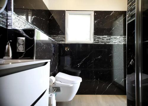 La salle de bains noire est pourvue de toilettes et d'une fenêtre. dans l'établissement VILLA SAINTE BAUME Piscine Jacuzzi tout confort, à Nans-les-Pins