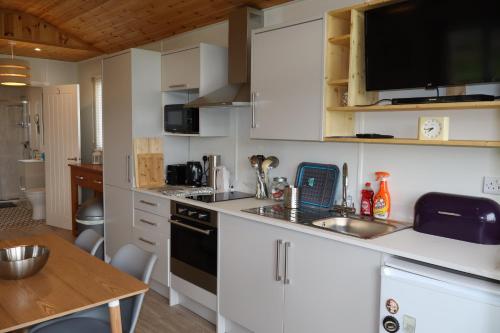 a kitchen with white cabinets and a sink and a table at Cabin Cynthia in Llwyngwril