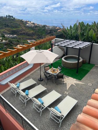 a patio with a table and chairs and an umbrella at House of the sun in Ponta do Sol