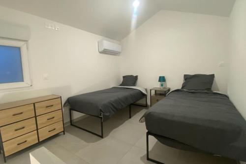 une chambre avec deux lits et une commode et une fenêtre dans l'établissement Maison évasion détente, à Crémieu